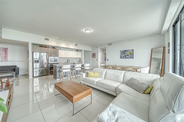 living room with sink, rail lighting, and light tile patterned floors