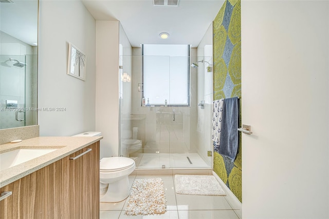 bathroom with a shower with door, vanity, toilet, and tile patterned floors