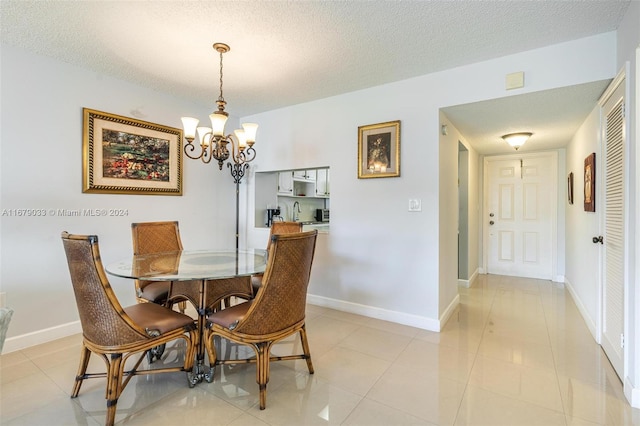 dining room with a textured ceiling, light tile patterned floors, and a chandelier