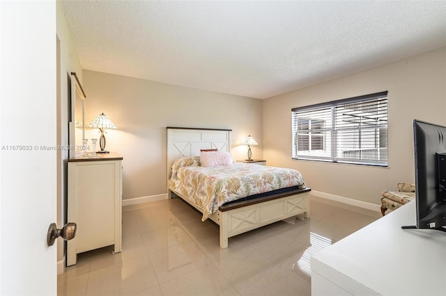 bedroom with a textured ceiling and light tile patterned floors