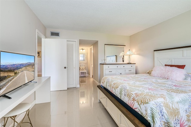 tiled bedroom with a closet and a textured ceiling