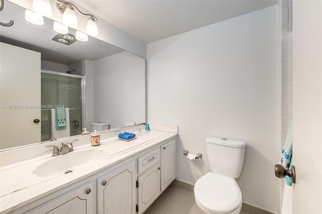 bathroom with toilet, vanity, tile patterned floors, and a shower with door