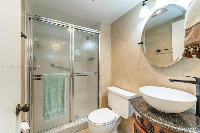 bathroom featuring vanity, a shower with shower door, and toilet