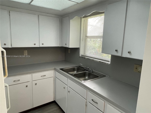 kitchen with dark wood-type flooring, white cabinetry, sink, and a textured ceiling