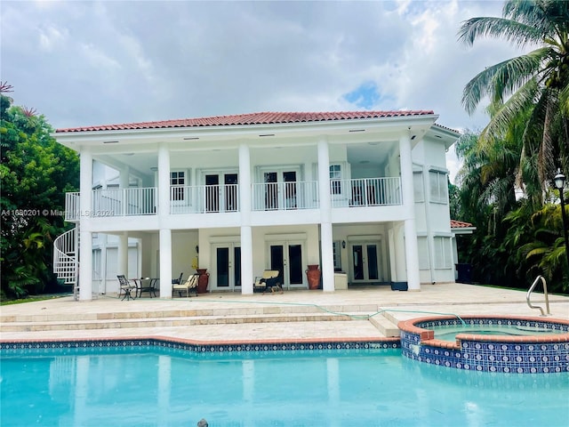 rear view of property featuring a patio, a pool with hot tub, and a balcony