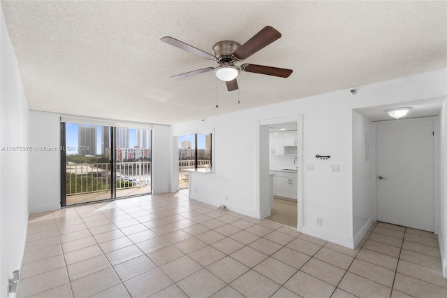 tiled spare room featuring a textured ceiling and ceiling fan