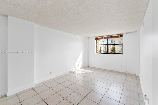 empty room featuring a textured ceiling and light tile patterned floors