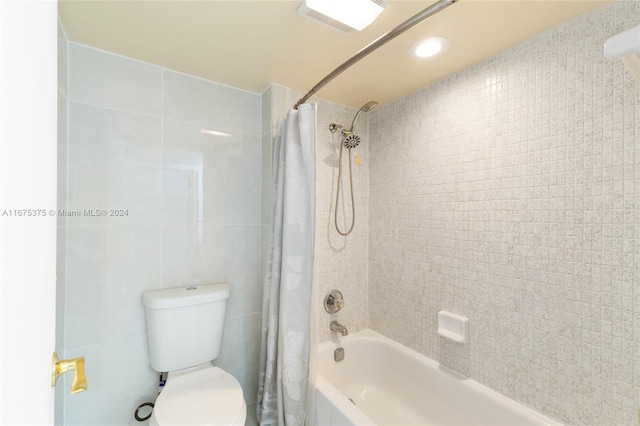 bathroom with toilet, tile walls, and shower / bath combo with shower curtain