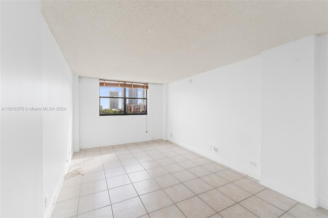 tiled empty room featuring a textured ceiling