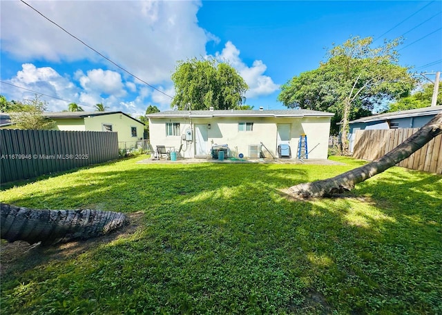 rear view of house featuring a patio area, a fenced backyard, a lawn, and stucco siding