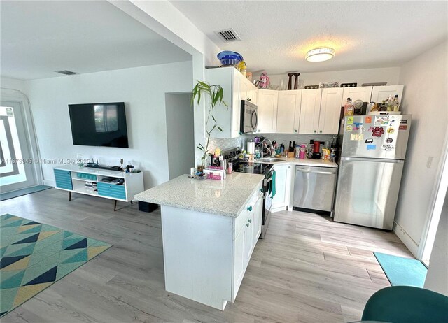 kitchen with appliances with stainless steel finishes, white cabinetry, and visible vents