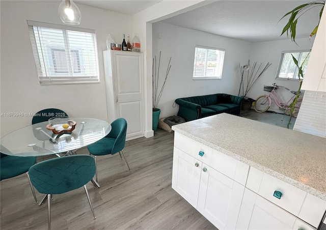 kitchen with a healthy amount of sunlight, light countertops, light wood-style flooring, and white cabinetry