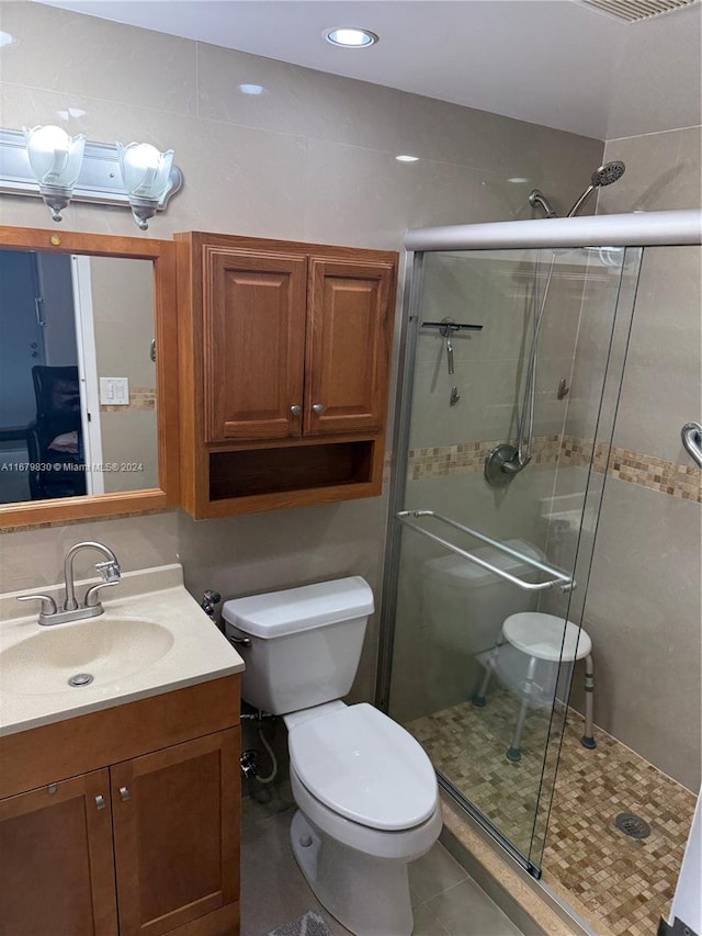 bathroom with vanity, walk in shower, toilet, and tile patterned flooring