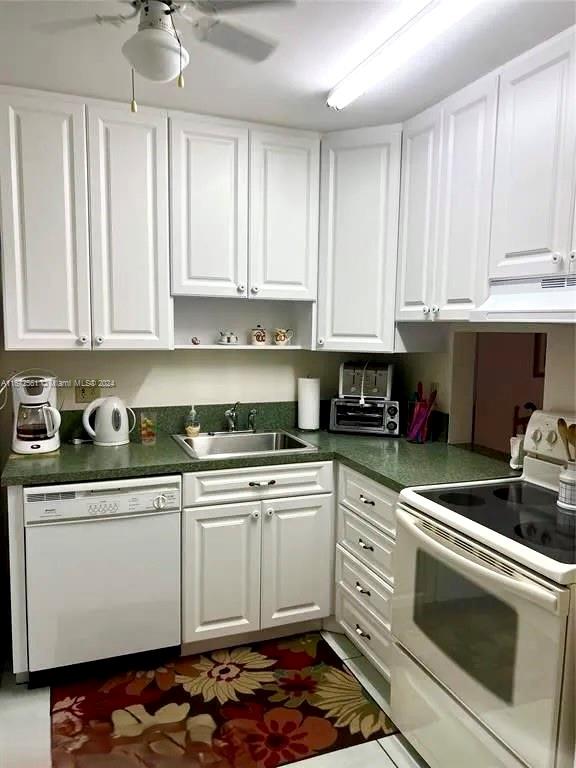 kitchen featuring white appliances, sink, ceiling fan, white cabinets, and range hood