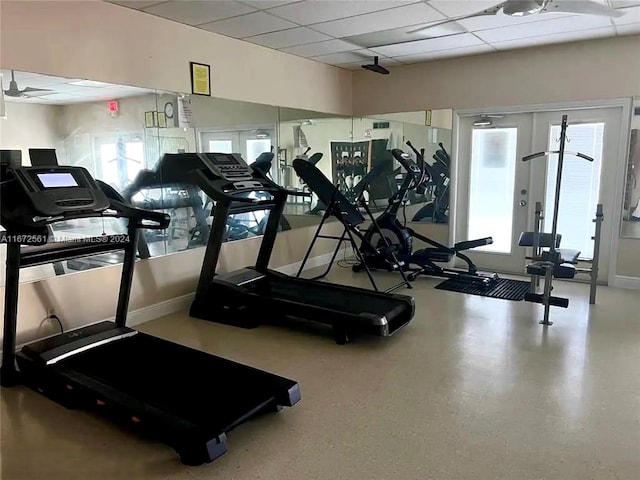 exercise room with a drop ceiling, a healthy amount of sunlight, and ceiling fan