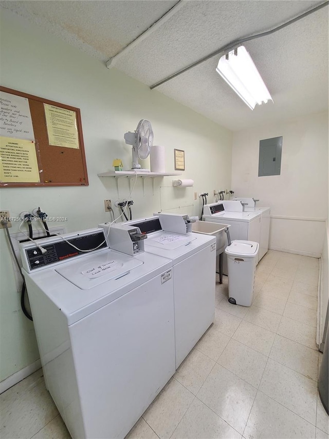 laundry area with electric panel, washer and clothes dryer, and a textured ceiling