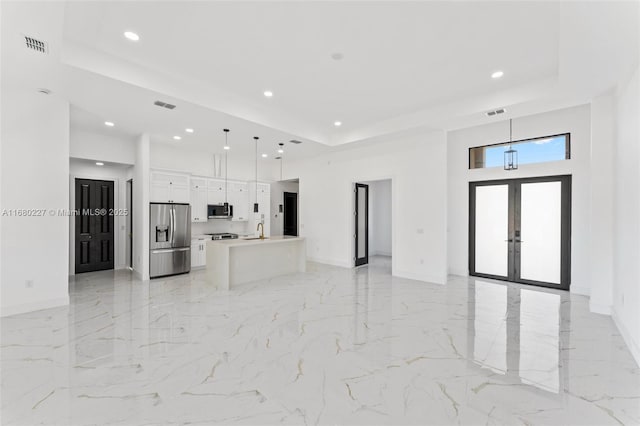 unfurnished living room with a raised ceiling, sink, and french doors