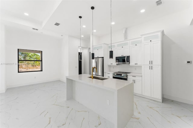 kitchen featuring sink, white cabinetry, a center island with sink, pendant lighting, and stainless steel appliances