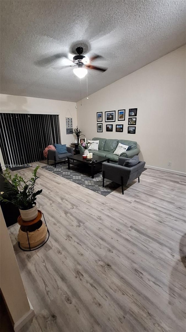 living room with light hardwood / wood-style floors, a textured ceiling, and ceiling fan