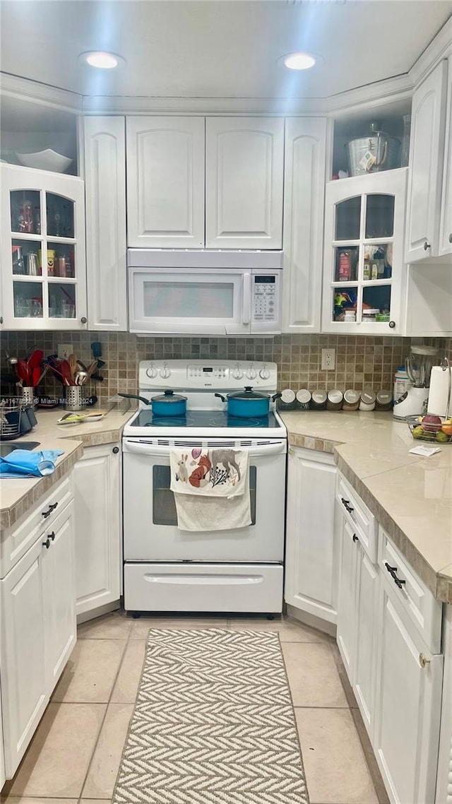 kitchen with white appliances, white cabinetry, light tile patterned floors, and decorative backsplash