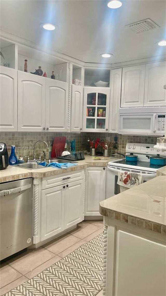 kitchen featuring white cabinets, light tile patterned floors, and white appliances