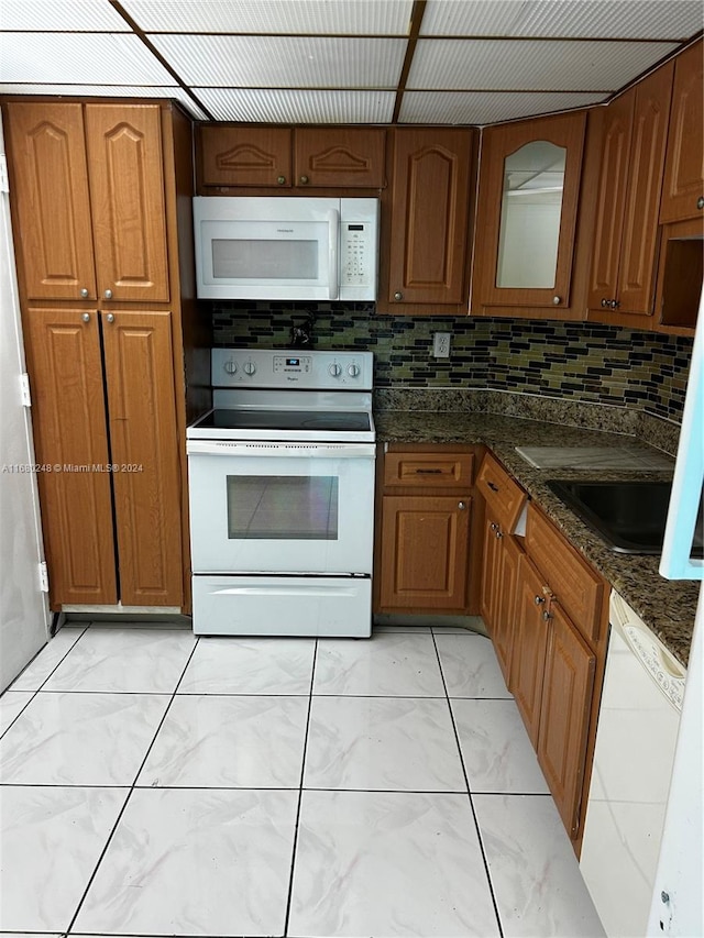 kitchen with decorative backsplash, dark stone counters, and white appliances