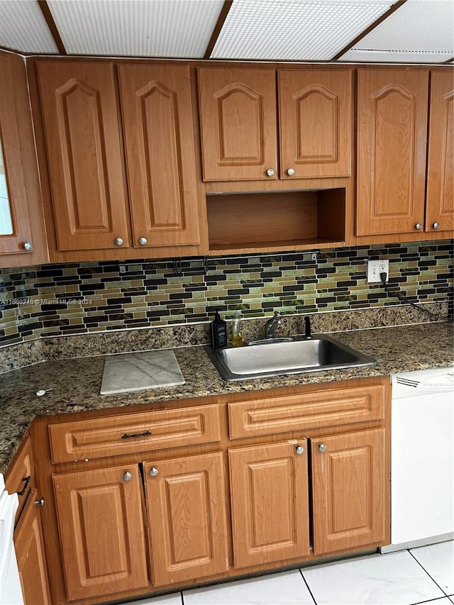 kitchen featuring white dishwasher, sink, backsplash, and light tile patterned floors