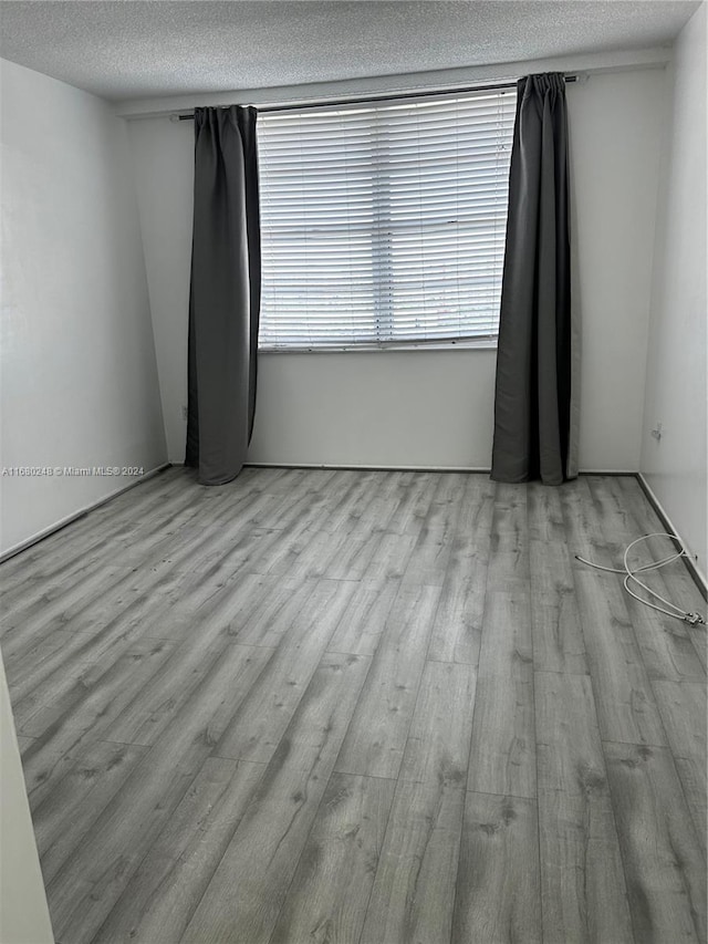 spare room featuring light hardwood / wood-style flooring and a textured ceiling