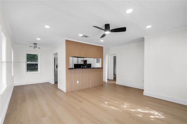 unfurnished living room featuring light wood finished floors, visible vents, arched walkways, a ceiling fan, and crown molding