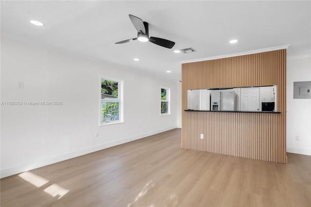 kitchen featuring crown molding, dark countertops, light wood-style floors, electric panel, and stainless steel fridge with ice dispenser