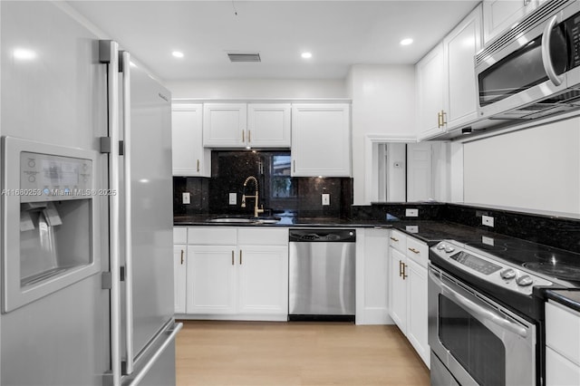 kitchen with white cabinetry, dark stone counters, and appliances with stainless steel finishes