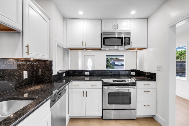 kitchen featuring stainless steel appliances, dark stone counters, and white cabinetry