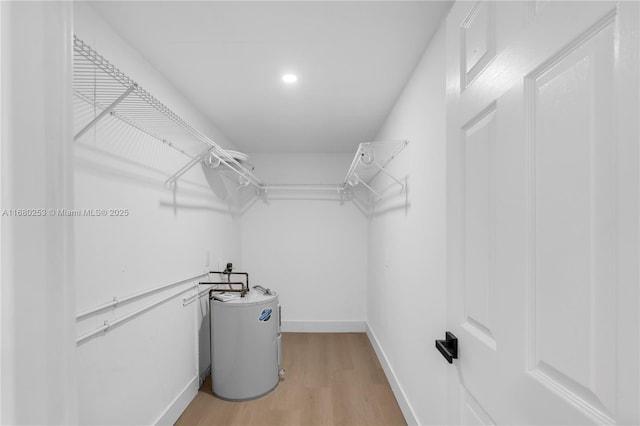 walk in closet featuring water heater and light hardwood / wood-style flooring