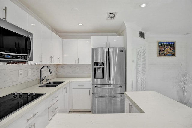 kitchen with tasteful backsplash, appliances with stainless steel finishes, sink, and white cabinets