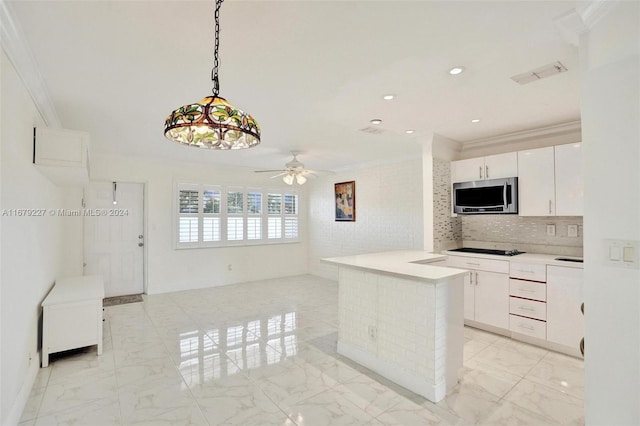 kitchen with hanging light fixtures, ceiling fan, stovetop, white cabinets, and crown molding