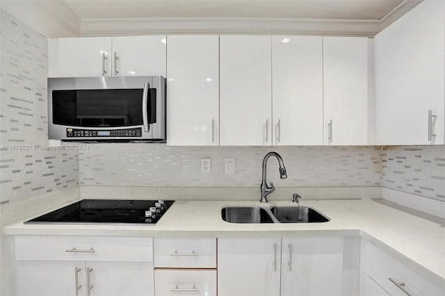 kitchen featuring black electric stovetop, tasteful backsplash, sink, and white cabinets