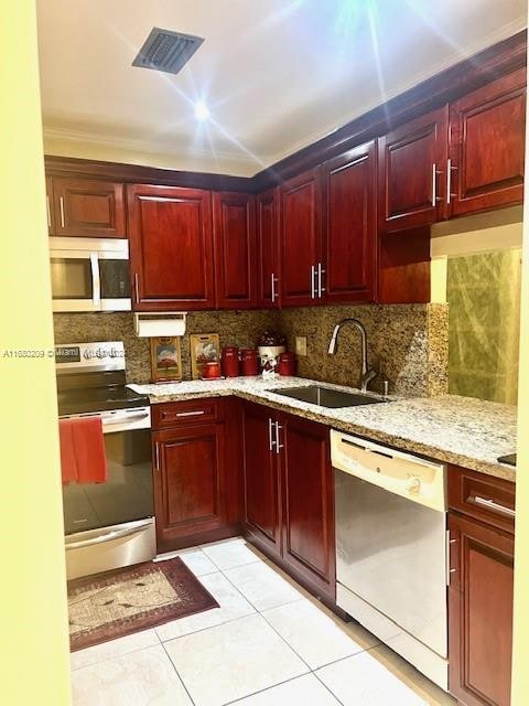 kitchen with stainless steel appliances, sink, light stone countertops, light tile patterned floors, and tasteful backsplash