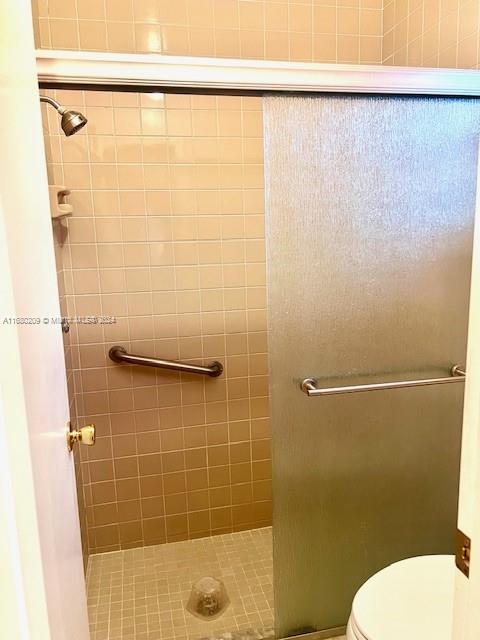 bathroom featuring tiled shower and toilet