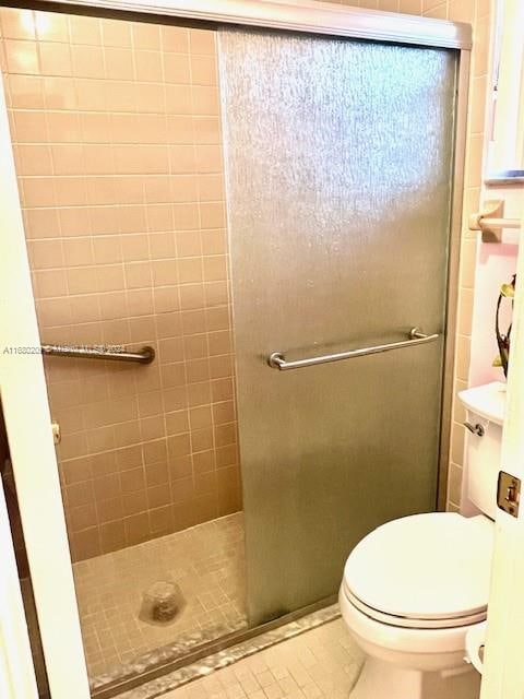 bathroom with toilet, tile patterned floors, and a shower with door