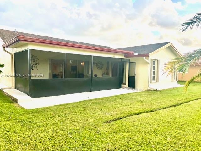 rear view of property featuring a yard and a sunroom