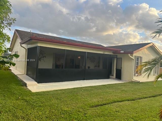 rear view of property with a yard and a sunroom