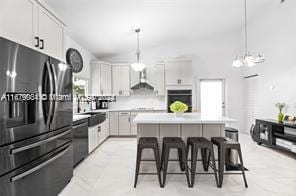 kitchen with white cabinets, black appliances, a kitchen island, and hanging light fixtures