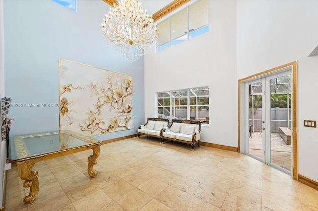 sitting room with french doors, a towering ceiling, and an inviting chandelier