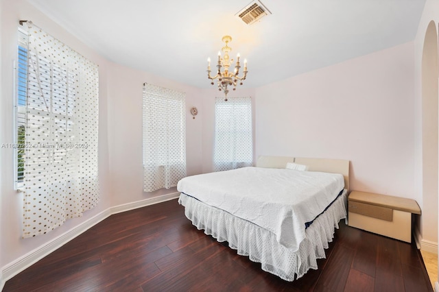 bedroom featuring an inviting chandelier and dark hardwood / wood-style flooring