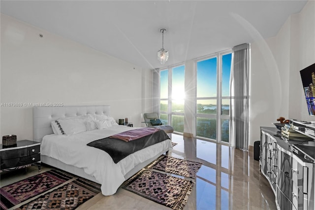 bedroom featuring a wall of windows and a notable chandelier