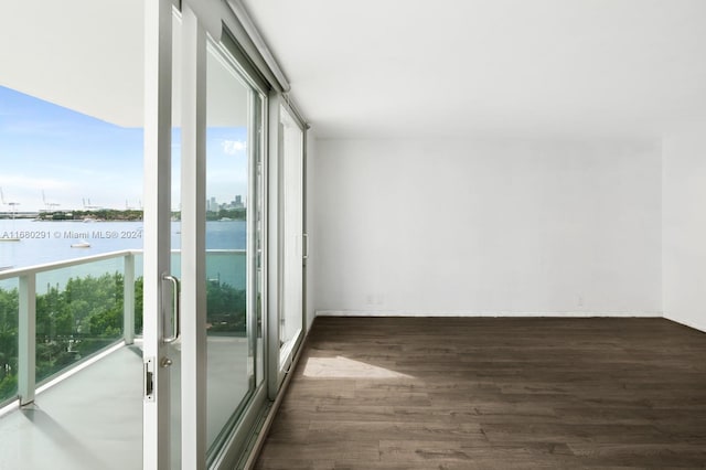 unfurnished room featuring plenty of natural light, dark hardwood / wood-style floors, and a water view