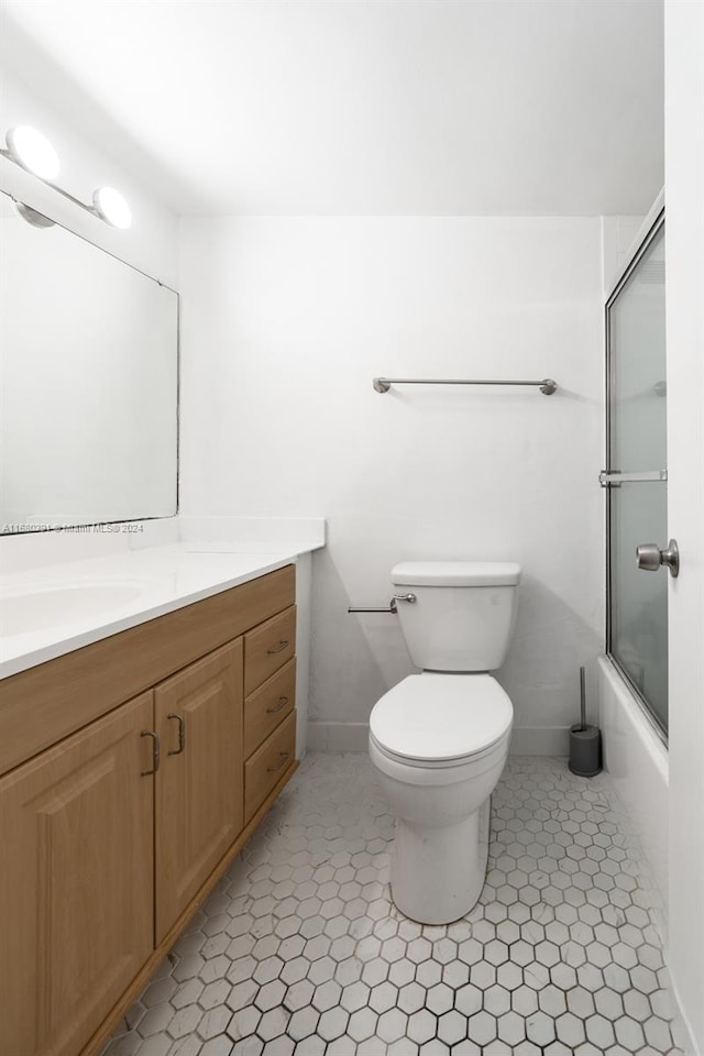 full bathroom featuring vanity, enclosed tub / shower combo, toilet, and tile patterned flooring