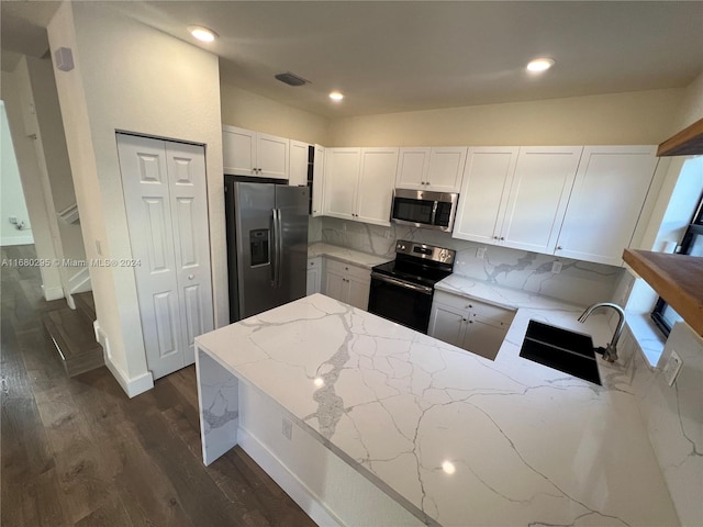 kitchen featuring light stone countertops, sink, dark hardwood / wood-style flooring, white cabinets, and appliances with stainless steel finishes