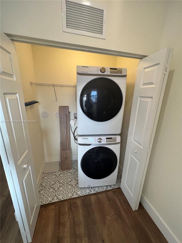 clothes washing area featuring dark hardwood / wood-style floors and stacked washer / drying machine