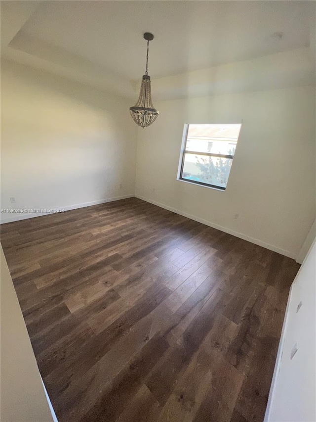 spare room featuring dark hardwood / wood-style floors and an inviting chandelier